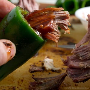 jalapeño peppers being stuffed with poasted pork shoulder and barbecue sauce