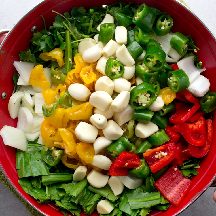 Homemade Puerto Rican Sofrito ingredients in a colander ... cilantro, culantro, Spanish onion, garlic, Ajicito peppers, long Italian peppers, red bell pepper.