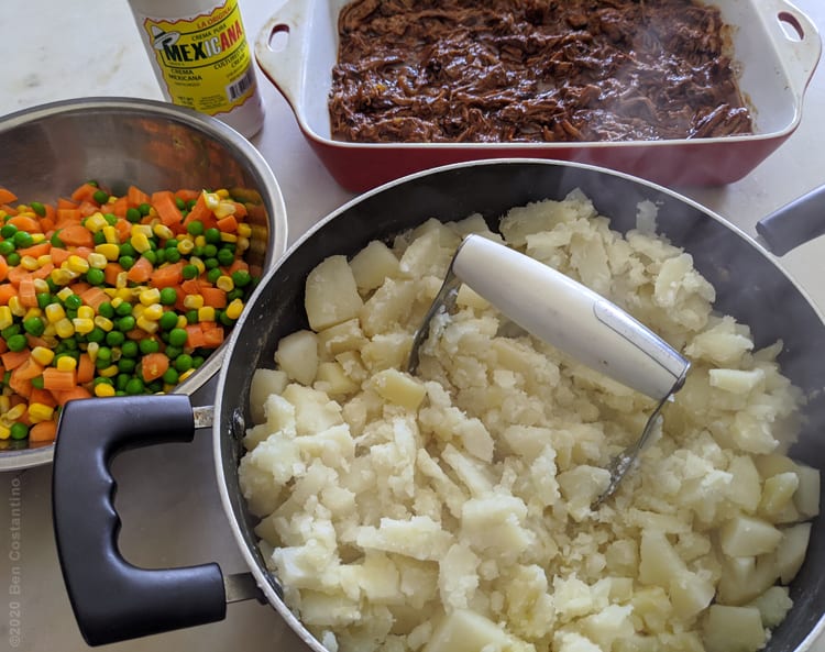 Shepherd's pie ingredients, mixed vegetables, braised beef and mashed potatoes being made with Mexican crema