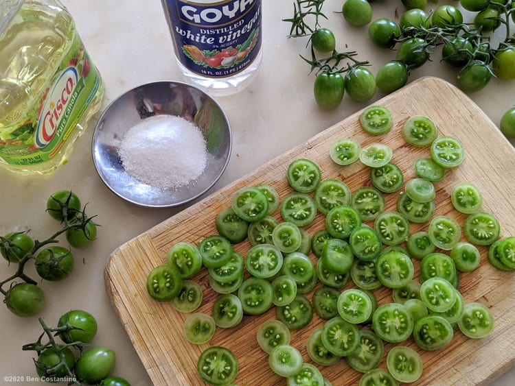 green cherry tomatoes sliced on a cutting board