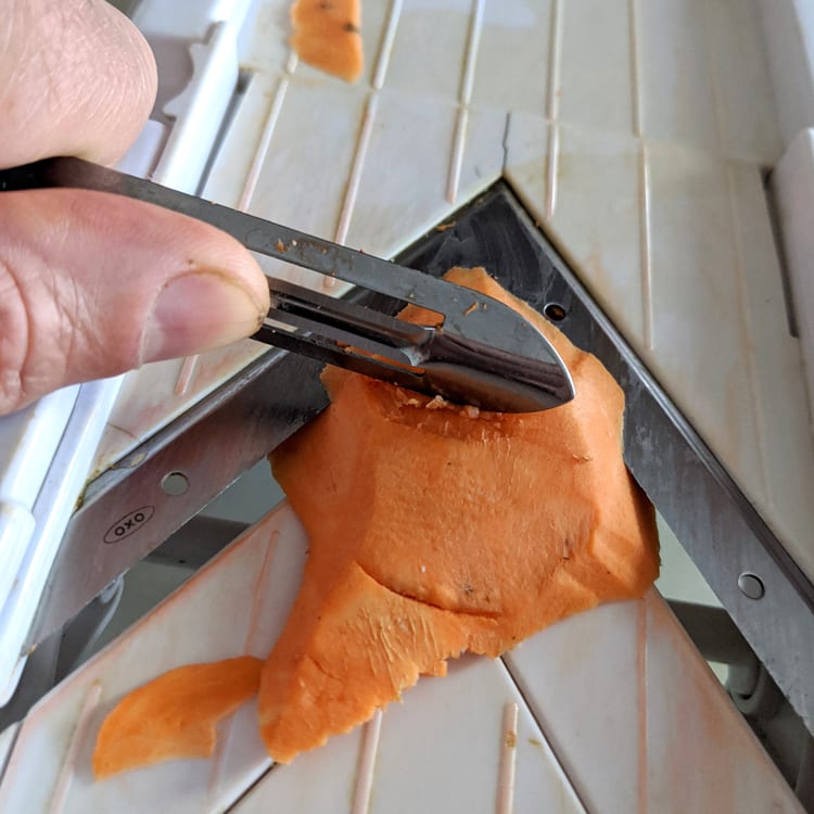 a vegetable peeler being used as a blade guard