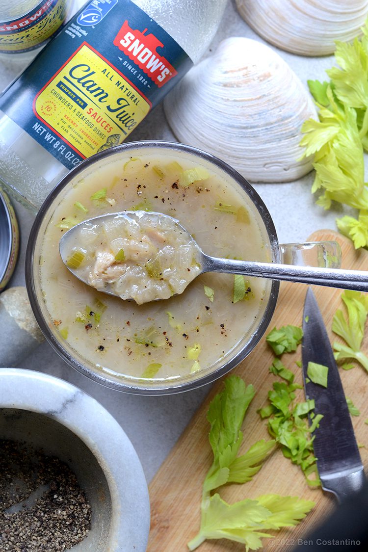 A spoonful of Rhode Island Clam Chowder garnished with celery leaves