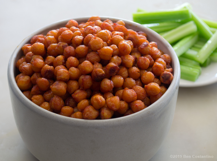 buffalo roasted chickpeas in a bowl served with celery sticks