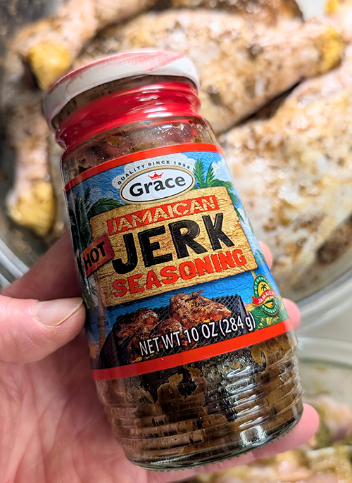 a jar of store-bought Jerk seasoning with it rubbed on some chicken