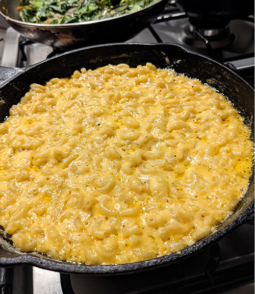 skillet-baked macaroni and cheese baked on a stovetop with collard greens